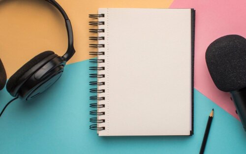 Ein Kopfhörer, ein Mikrophon, ein Block und Stift liegen auf einer bunten Unterlage. | © EnableMe