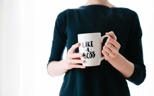 Eine Frau hält einen Kaffeebecher mit der Aufschrift "Like A Boss" vor ihren Oberkörper | © Brooke Lark / unsplash