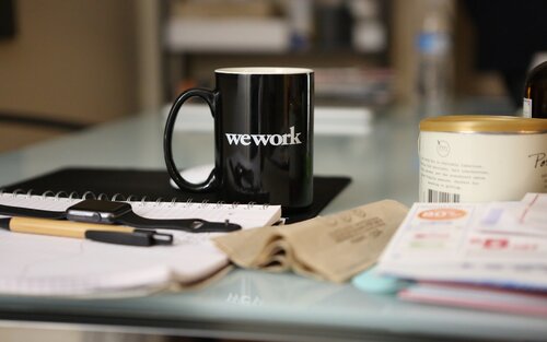 Arbeitsplatz mit Kaffeebecher "wework" | © unsplash