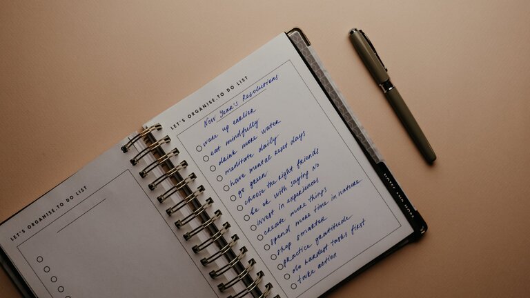 Foto eines Notizbuchs auf einem weißen Tisch, in dem eine To-Do-Liste aufgeführt ist. | © pexels
