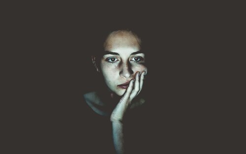 Eine junge Frau, die im Dunkeln vor einem hellen Bildschirm sitzt. Dieser beleuchtet sie, während um sie herum alles schwarz ist. | © Niklas Hamann/unsplash