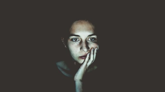 Frau, die im Dunkeln vor einem hellen Bildschirm sitzt | © Niklas Hamann/unsplash