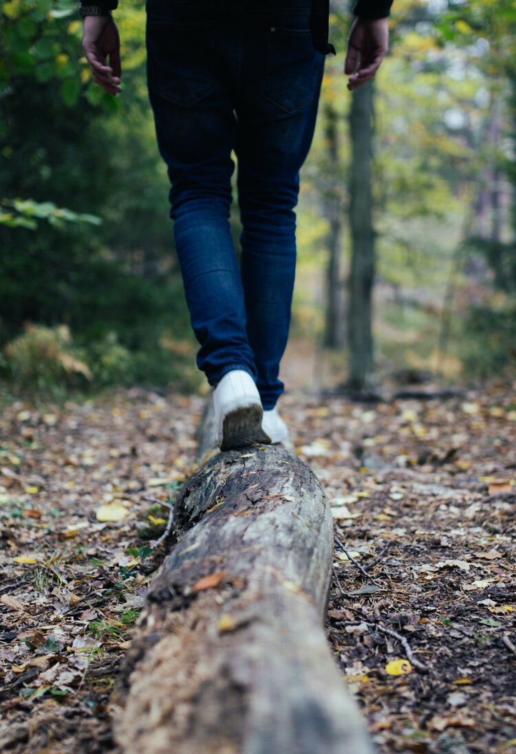 Eine Person balanciert auf einem Baumstamm im Wald. | © Jon Flobrant/unsplash