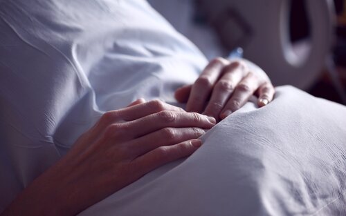 Person, die im Krankenhausbett sitzt und ihre Hände über den Bauch verschränkt | © pixabay