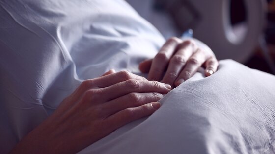 Person, die im Krankenhausbett sitzt und ihre Hände über den Bauch verschränkt | © pixabay