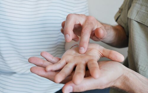 Nahaufnahme von Händen: ein erwachsener Mann hält die Hand eines Kindes und zeichnet mit dem Zeigefinger der anderen Hand in die Handinnenfläche | © DBSV