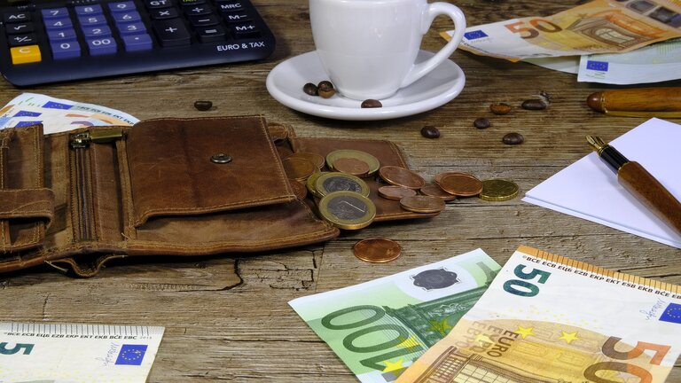 Kaffee-Tasse, Portemonnaie, Taschenrechner, Münzen und Noten auf einem Tisch.  | © pixabay