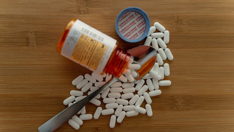 Das Bild zeigt eine ausgekippte Tablettendose. Die Tabletten liegen verstreut auf einer Fläche und auf einen Löffel.  | © unsplash
