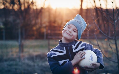 Junge mit Fußball unter dem Arm lächelt in die Kamera | © unsplash