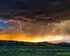 Eine Landschaft mit Wiesen, Bäumen und Bergen. Im Himmel ein Sonnenuntergang sowie düstere Gewitterwolken und Blitze. | © pixabay