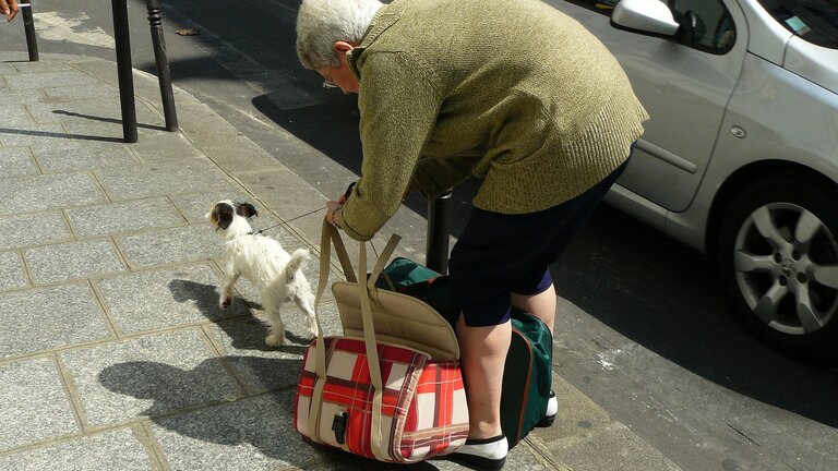Ältere Frau bückt sich um Taschen aufzuheben  | © pixabay