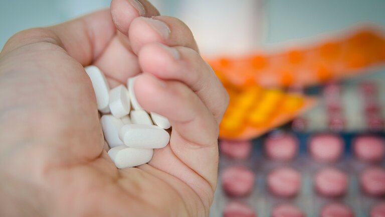 Hand mit Tabletten und anderen Medikamenten im Hintergrund | © pixabay