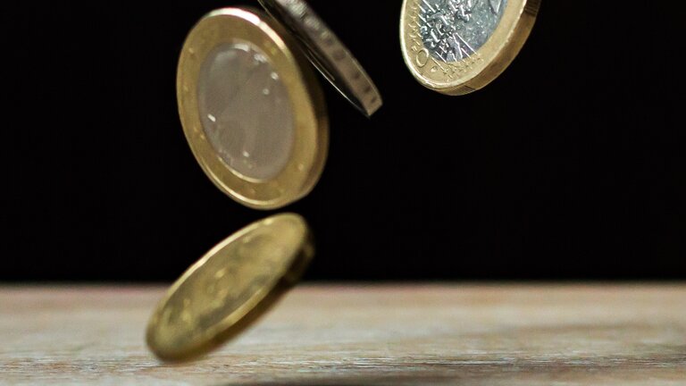 Euromünzen fallen auf einen Tisch. | © Pexels