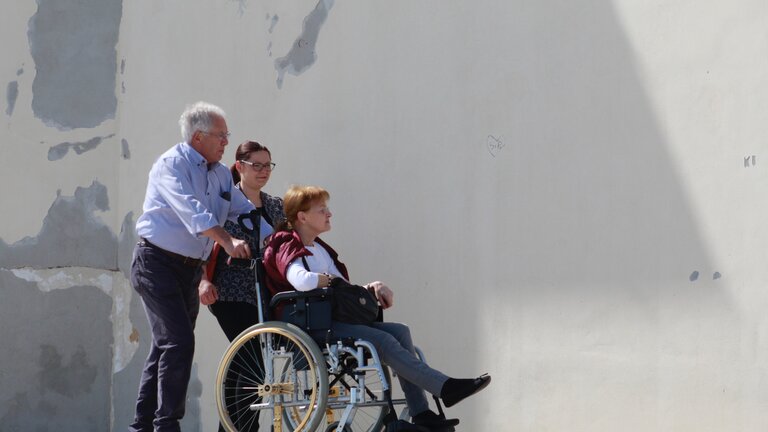Drei Personen auf einem Gehweg, wovon eine Person im Rollstuhl sitzt | © Stefano Intintoli/unsplash