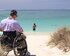 Ein Mann sitzt im Rollstuhl an einem Strand und blickt auf das Meer. | © pixabay