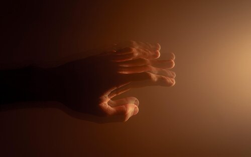 Eine verschwommene, zitternde Hand vor einem braunem Hintergrund  | © AnnyksPhotography / pixabay.com