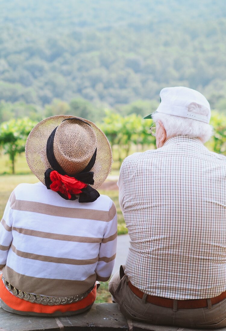 Eine ältere Frau und ein älterer Mann blicken über eine Obstplantage | © Christian Bowen/unsplash