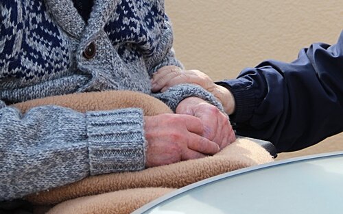 die Hände eines Rollstuhlfahrers liegend auf dessen Schoß werden von einer weiteren Person gehalten | © pixabay