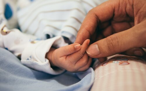 Foto von zwei Fingern, die eine Babyhand halten. | © Unsplash