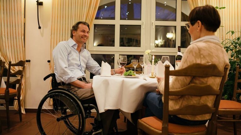 Mann im Rollstuhl mit einer Dame beim Essen | © Investitions- und Marketinggesellschaft Sachsen-Anhalt mbH, Harald Krieg