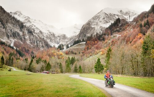 Ein Mann fährt im Rollstuhl unterhalb einer Berglandschaft. | © erlebe.bayern – Tobias Gerber
