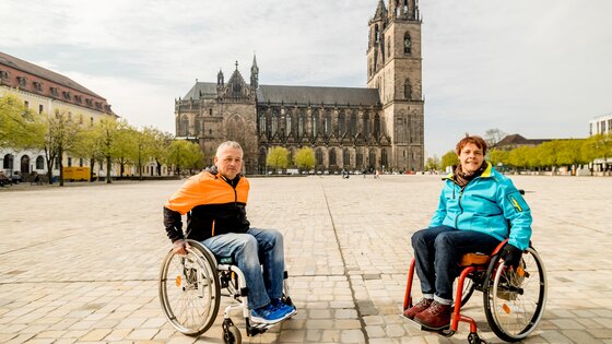 Zwei Personen im Rollstuhl posieren auf einem Platz vor dem Dom in Magdeburg.  | © Magdeburg Marketing, Andreas Lander