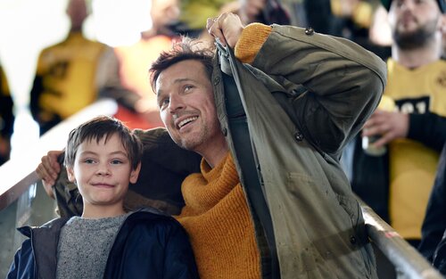 der Vater Mirco hält schützend seine Jacke um seinen Sohn Jason | © Szenenbild Wochenendrebellen I JETZT & MORGEN GbR
