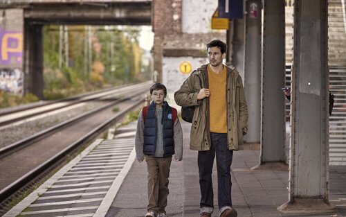 Szenenbild von Mirco (Florian David Fitz) und Jason (Cecilio Andresen) am Bahnsteig. | © Szenenbild Wochenendrebellen I JETZT & MORGEN GbR