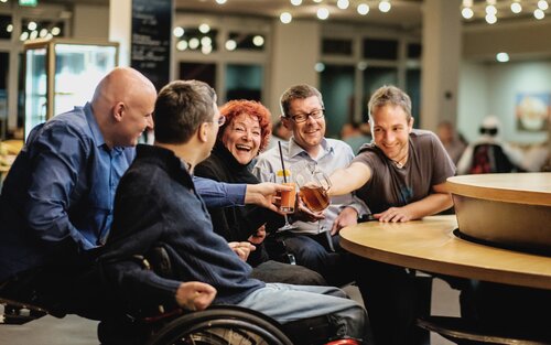 Menschen mit Behinderungen in Interaktion mit ihren Assistenzen in einer Bar. | © Andi Weiland/Gesellschaftsbilder.de