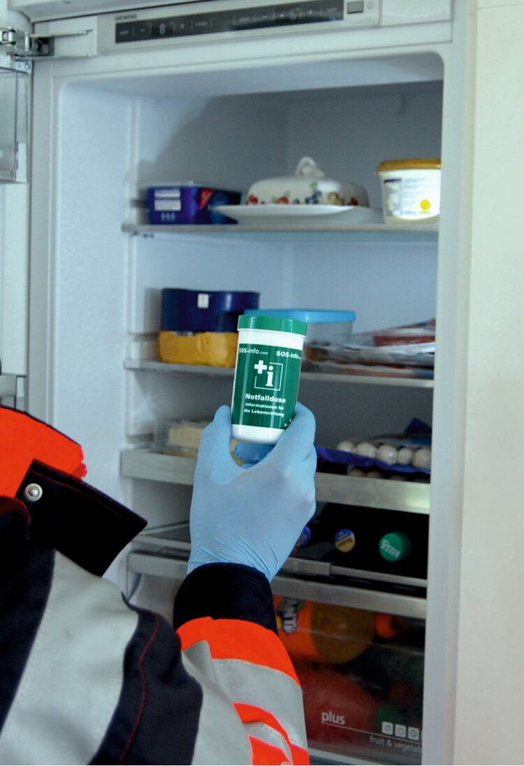 Eine Rettungskraft, die eine Notfalldose in einem Kühlschrank findet | © acavi GmbH