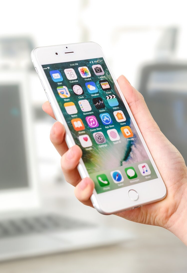 Eine Person hält ein Smartphone der Marke Apple in der Hand. Der Bildschirm ist entsperrt und es sind App Symbole zu sehen. | © pixabay.com