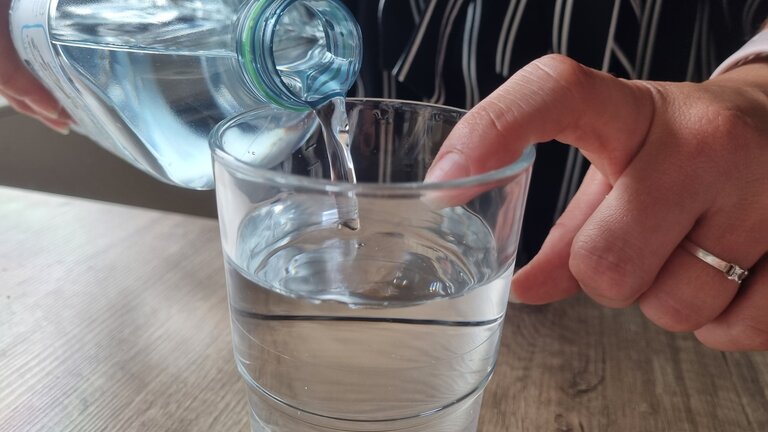 Es wird ein Glas aufgefüllt mit Wasser. Als Richtwert wird ein Finger am Glas platziert. | © Vanessa Cermelj