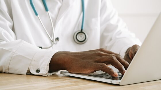 Arzt im weißen Kittel und Stetoskop um den Hals tippt auf einem Laptop | © Ivan Samkov/pixabay.com