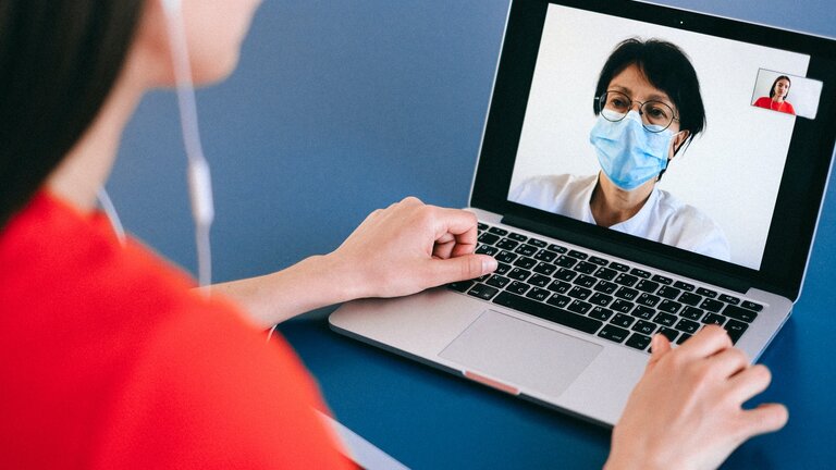 Eine Frau mit Kopfhörern sitzt vor einem Laptop und führt ein Videogespräch mit einer Ärztin | © Anna Shvets/pexels.com