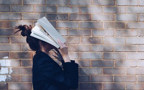 Eine Frau hält ein Buch vor ihr Gesicht | © unsplash