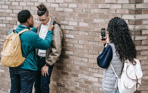 Ein Junge drückt einen anderen Jungen an eine Wand – ein Mädchen filmt dies mit ihrem Smartphone | © Keira Burton / pexels