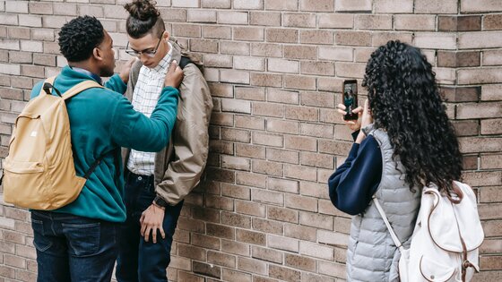 Ein Junge drückt einen anderen Jungen an eine Wand – ein Mädchen filmt dies mit ihrem Smartphone | © Keira Burton / pexels