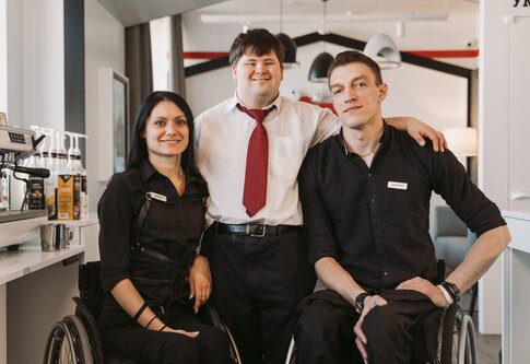 Zwei Mitarbeitende im Rollstuhl und ein Kollege mit Trisomie-21 Lächeln in die Kamera | © pexels