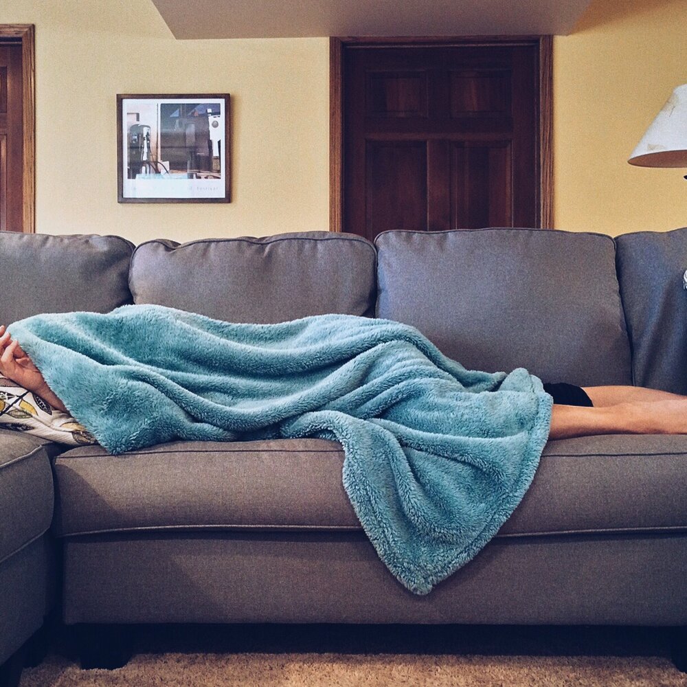 Jemand liegt auf der Couch mit einer Decke über den Kopf | © pexels.com
