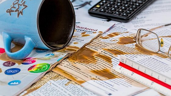 eine umgestoßene Kaffeetasse liegt auf Zeitschriften | © pixabay.com