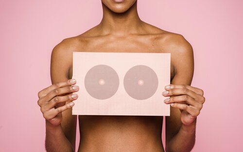 Eine Frau hält ein Schild mit Brüsten vor ihre Brüste | © Klaus Nielsen / pexels