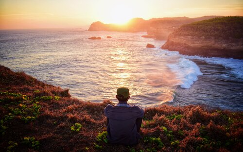 Ein Mann sitzt an einer Klippe und betrachtet den Sonnenuntergang | © Haydan Assoendawy / pexels