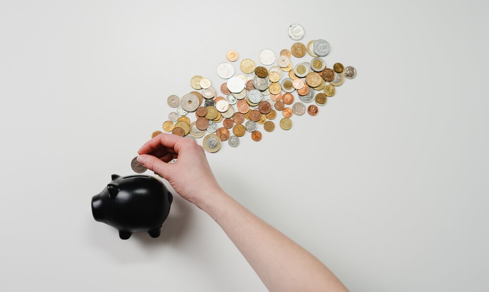 in ein schwarzes Sparschwein werden Münzen eingeworfen | © cottonbro/ pexels.com