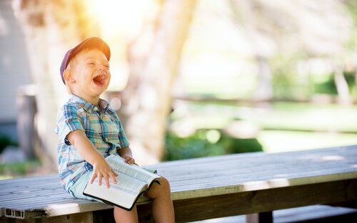 Ein kleiner Junge sitzt auf der Bank und lacht fröhlich | © unsplash