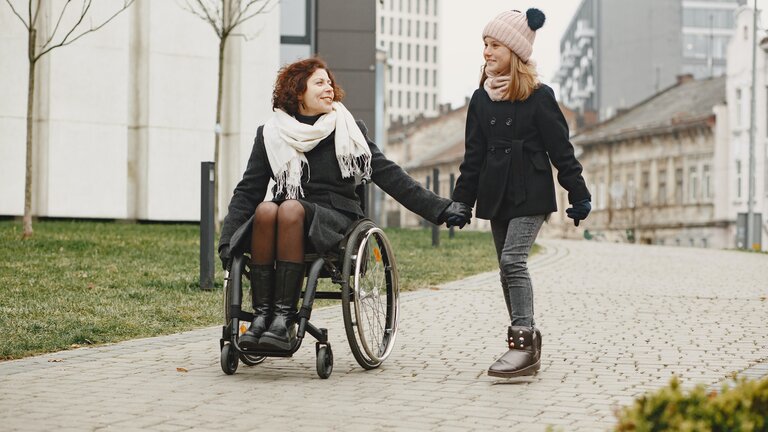 Eine Mutter im Rollstuhl geht mit ihrer Tochter spazieren | © pexels
