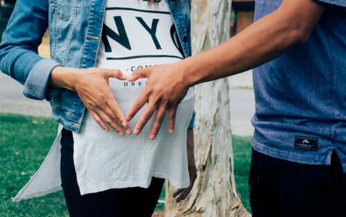 Ein Pärchen bildet mit den Händen ein Herz vor dem Bauch der Schwangeren | © pexels