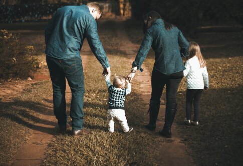 Ein Mann und eine Frau führen in der Mitte ein kleines Kind an der Hand. Rechts neben der Frau läuft ein Mädchen an ihrer Hand. | © Vidal Balielo/pexels.com