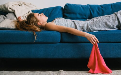 Eine junge Frau liegt auf einem blauen Sofa. Einen Arm hält sie dabei über den Kopf, der andere Arm hängt leicht über das Sofa hinaus und hält ein rotes Tuch in der Hand.  | © Pexels