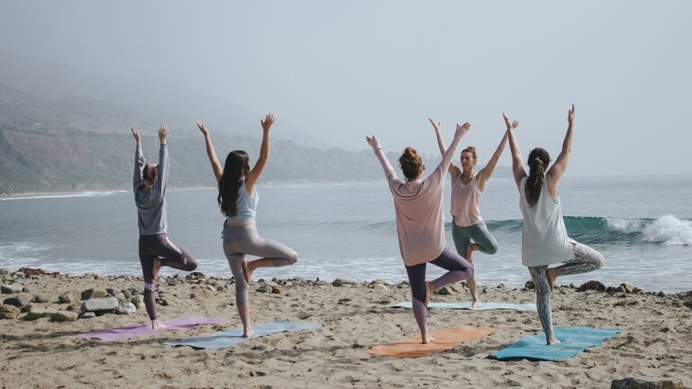 Mehrere Menschen machen Yoga am Strand | © Kaylee Garrett/unsplash