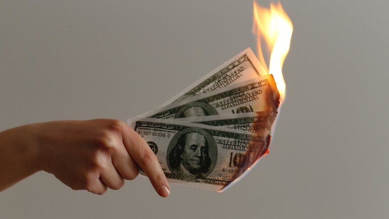 Hand hält Geldscheine, die brennen. | © unsplash